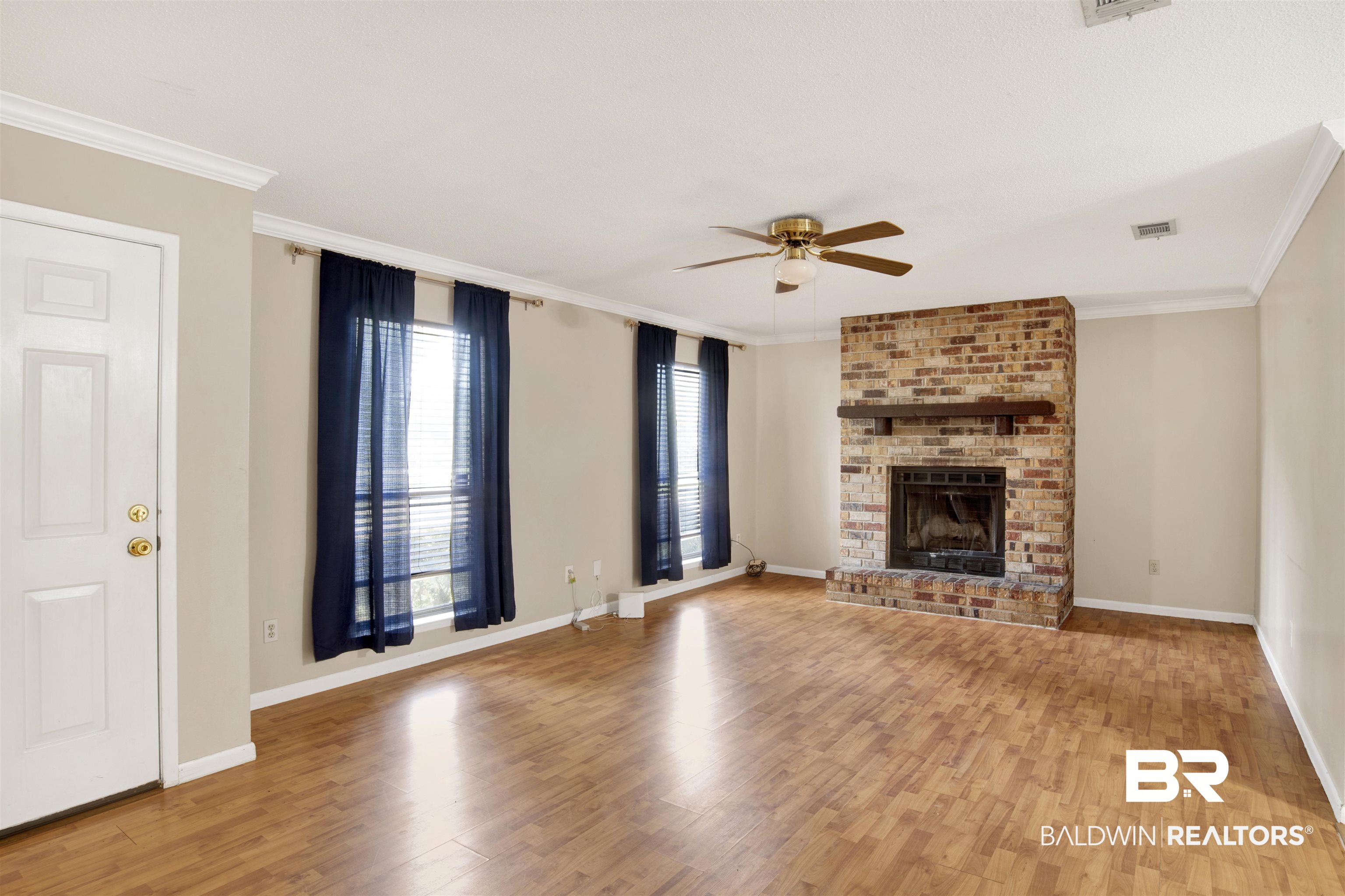 3560 Creekway Road Mobile, AL 36619 - Photo 11 of 24 Unfurnished living room featuring light hardwood / wood-style flooring, ceiling fan, brick wall, a fireplace, and ornamental molding