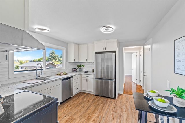 a kitchen with stainless steel appliances a sink a stove a refrigerator cabinets and dining table