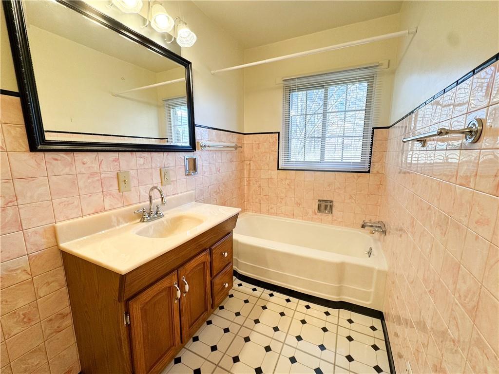 618 New Castle Road Butler, PA 16001 - Photo 16 of 23 a bathroom with a sink a mirror and a bathtub with a window