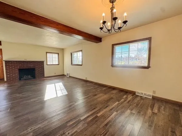 a view of empty room with wooden floor and fireplace