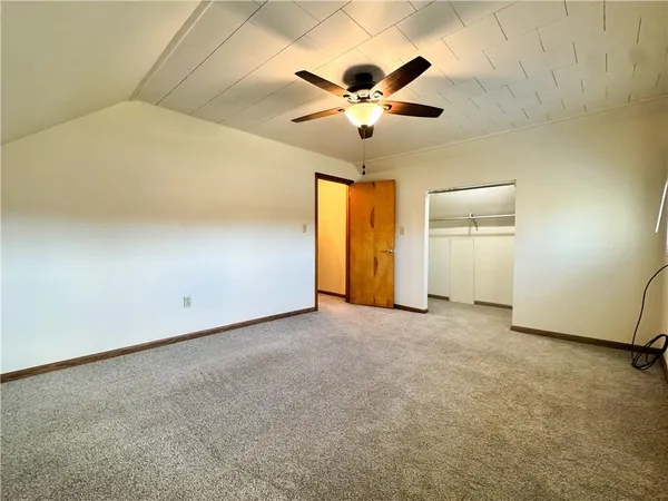an empty room with chandelier fan and windows