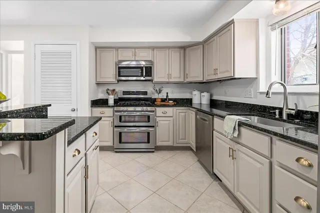 a kitchen with stainless steel appliances granite countertop a stove top oven a sink a dining table and chairs