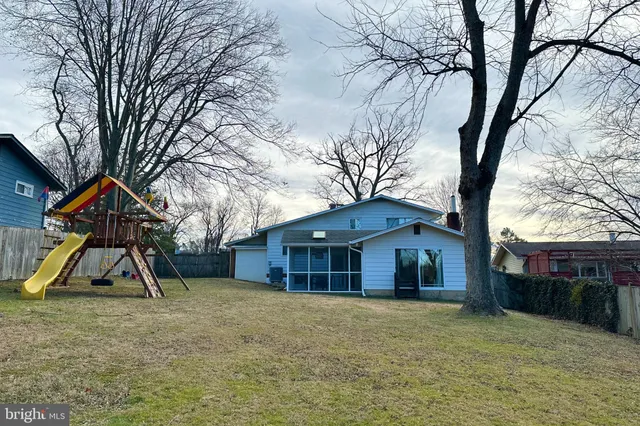 a view of a house with a yard and a large tree