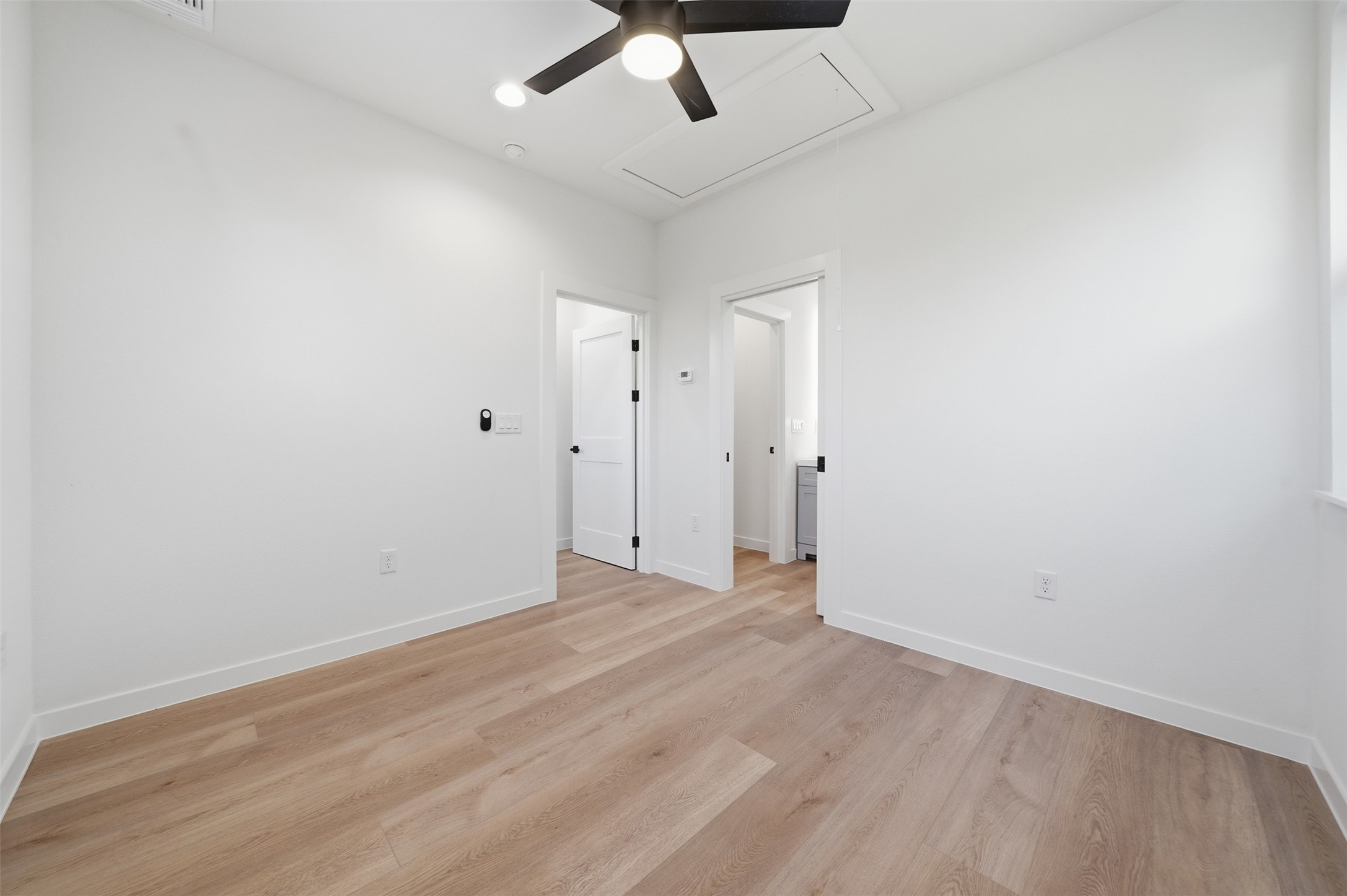2212 Yellow Jacket Lane, Unit 2 Austin, TX 78741 - Photo 17 of 25 Spacious room featuring light wood-finish flooring, crisp white walls, and a contemporary black ceiling fan