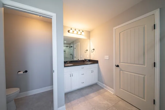 a bathroom with a granite countertop sink a toilet and a mirror