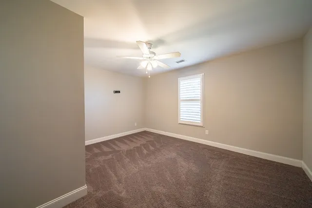an empty room with windows and ceiling fan