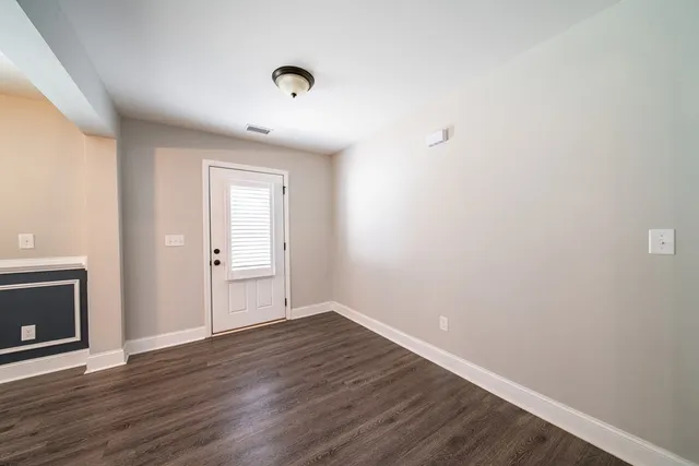 a view of an empty room with wooden floor and a fireplace