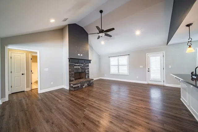 an empty room with wooden floor fireplace and windows