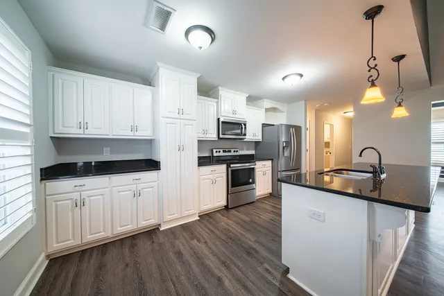 a kitchen with granite countertop a sink a counter top space stainless steel appliances and cabinets