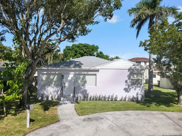 an aerial view of a house with a yard and a large tree