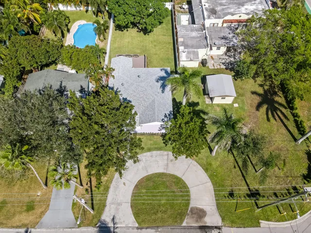 an aerial view of a house with a yard and a large tree