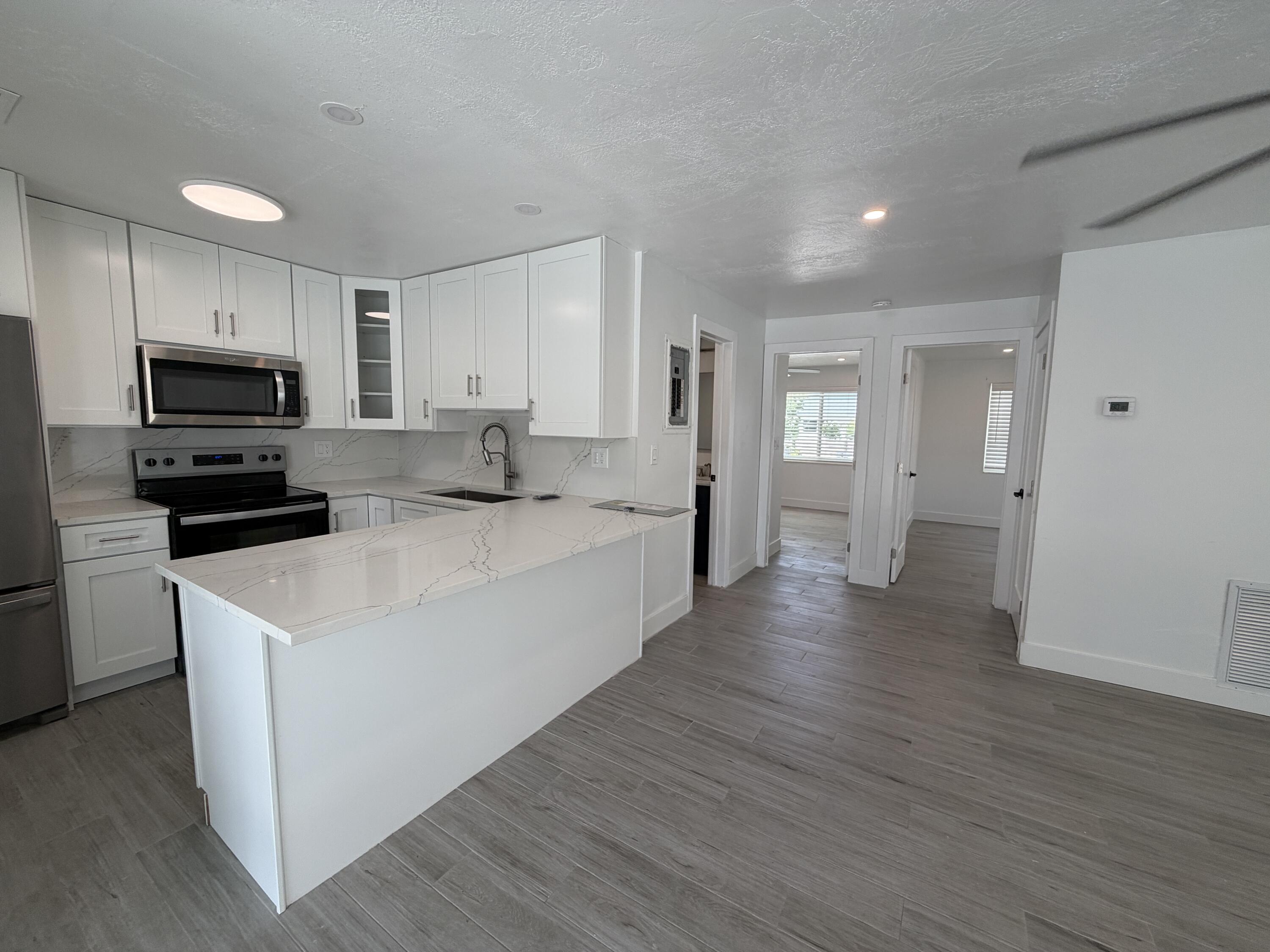29656 Constitution Avenue Big Pine Key, FL 33043 - Photo 16 of 19 a large white kitchen with kitchen island a sink dishwasher a stove and a refrigerator with wooden floor