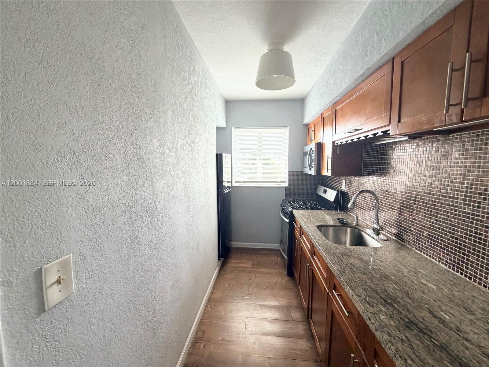 620 84th Street, Unit 25 Miami Beach, FL 33141 - Photo 1 of 12 a kitchen with stainless steel appliances granite countertop a sink and a stove