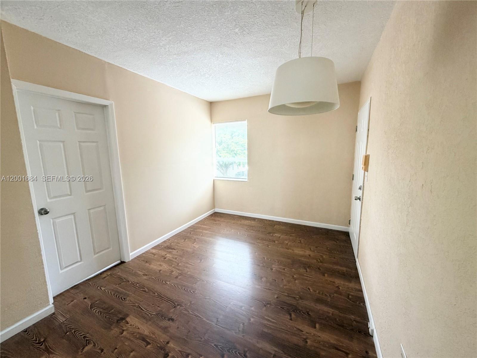 620 84th Street, Unit 25 Miami Beach, FL 33141 - Photo 3 of 12 an empty room with wooden floor and windows
