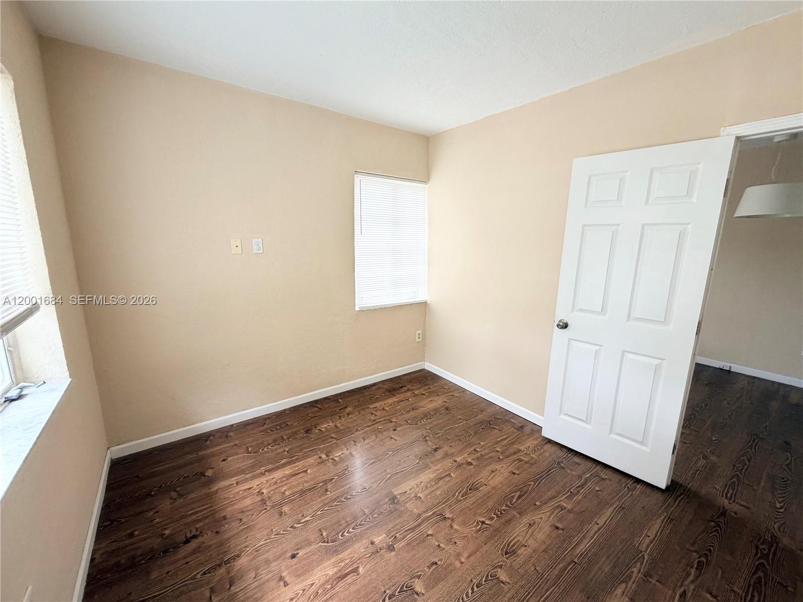 620 84th Street, Unit 25 Miami Beach, FL 33141 - Photo 9 of 12 an empty room with wooden floor and windows
