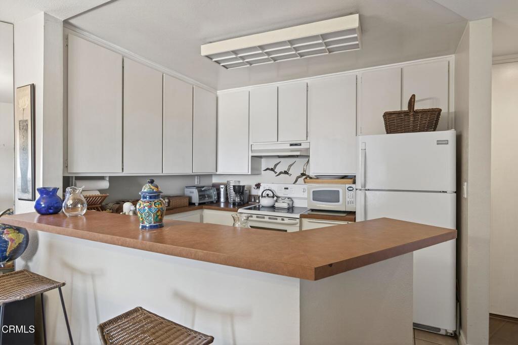 2901 Peninsula Road, Unit 333 Oxnard, CA 93035 - Photo 5 of 14 a kitchen with a sink a stove and white cabinets