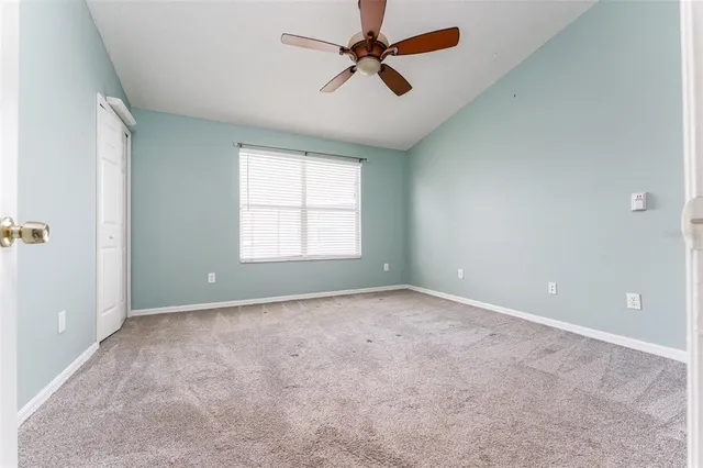 an empty room with closet and a ceiling fan