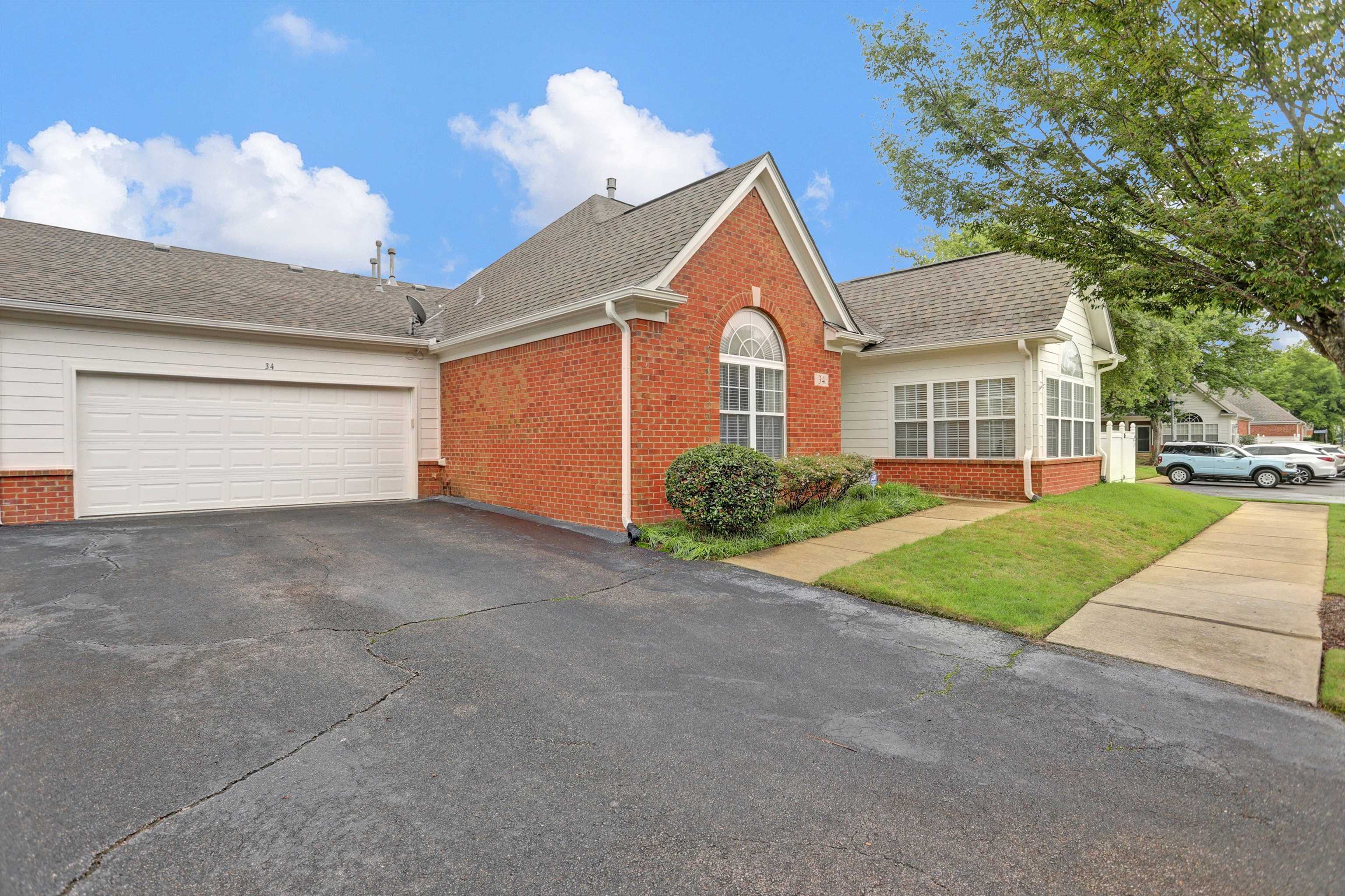 34 Peyton Ridge Drive, Unit 21 Collierville, TN 38017 - Photo 4 of 37 Brick and siding exterior featuring a two-car garage, pitched shingle roof, and an arched window
