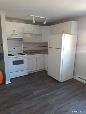 a kitchen with granite countertop white cabinets and white appliances