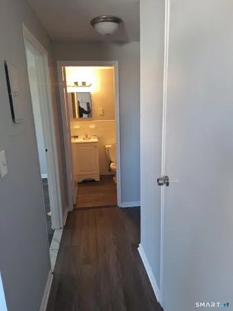 a view of a hallway with wooden floor and a bathroom
