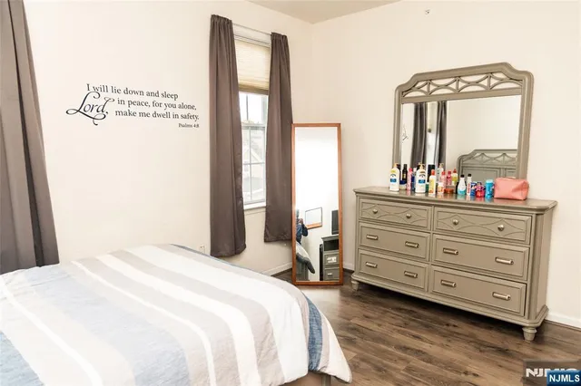 a bedroom with a bed a mirror on dresser and a window