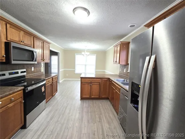 a large kitchen with stainless steel appliances granite countertop a stove a sink dishwasher a refrigerator and a stove top oven