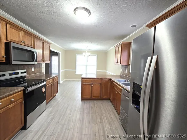 a large kitchen with stainless steel appliances granite countertop a stove a sink dishwasher a refrigerator and a stove top oven