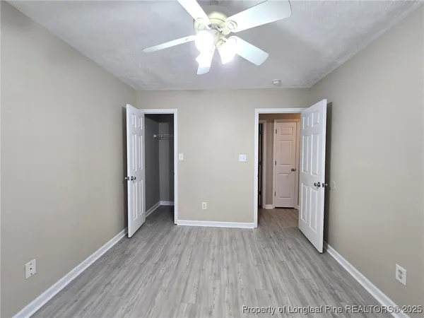 an empty room with closet and a ceiling fan