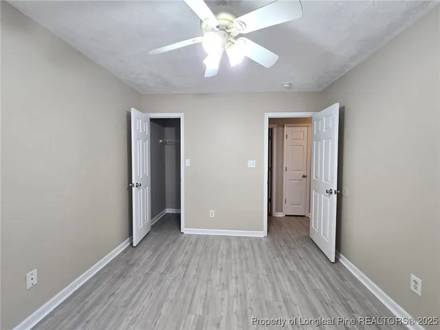 an empty room with closet and a ceiling fan