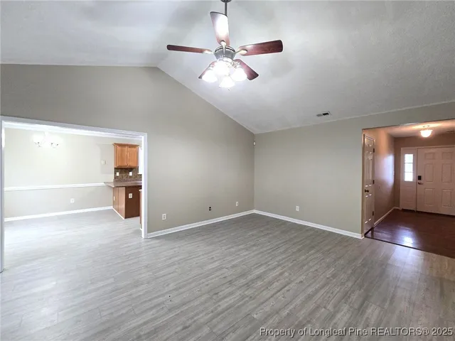 a view of an empty room with window and wooden floor