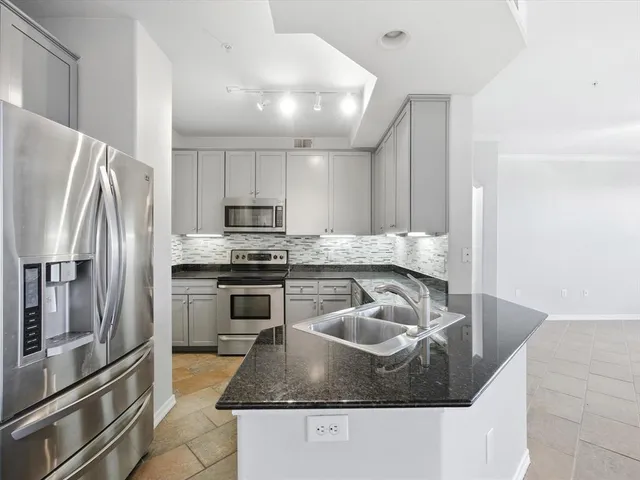 a kitchen with stainless steel appliances granite countertop a sink a stove and a refrigerator