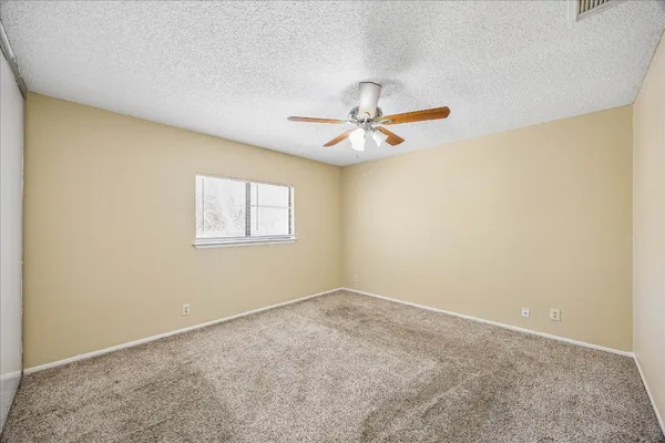 an empty room with a window and a fan