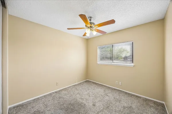 an empty room with a window and a ceiling fan