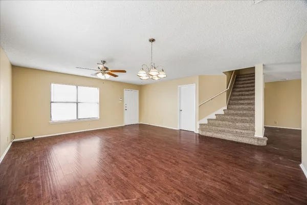 an empty room with wooden floor chandelier and windows