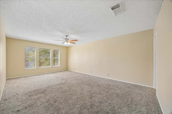 an empty room with windows and chandelier fan