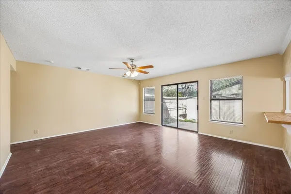 a view of an empty room with a window and wooden floor