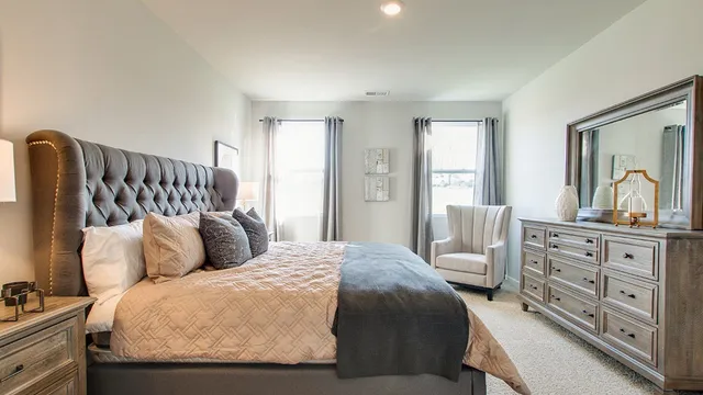 a bedroom with a bed a dresser and next to a window