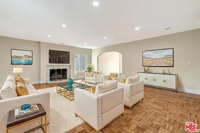 a living room with furniture a flat screen tv and a refrigerator