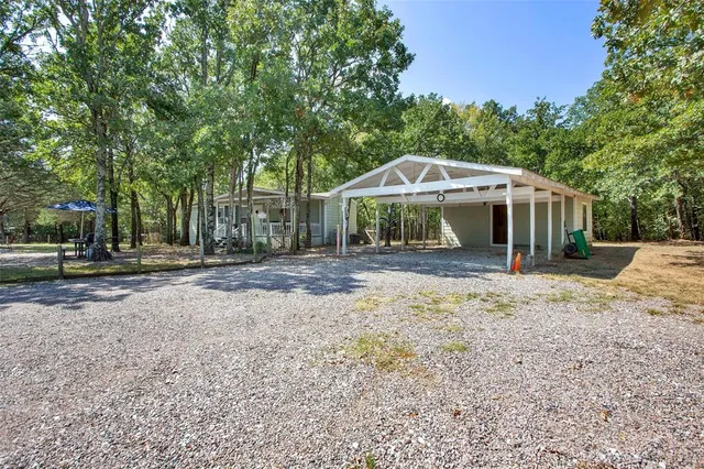 a view of a house with a yard and large trees