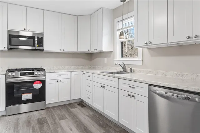 a kitchen with granite countertop white cabinets and stainless steel appliances
