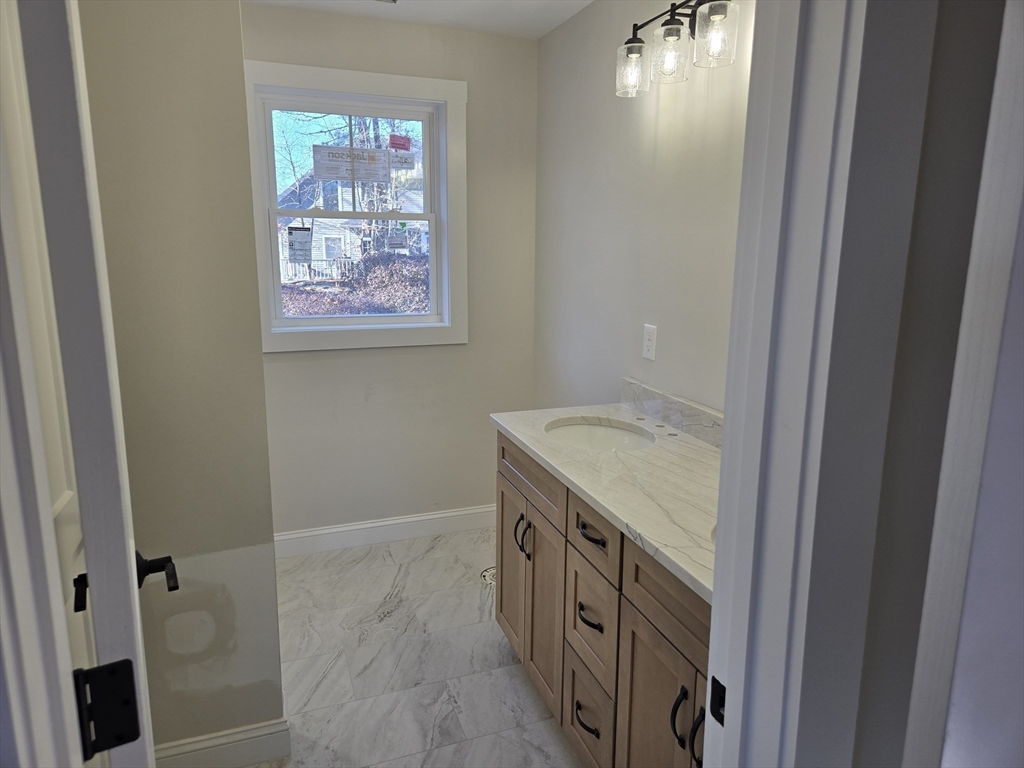 39 Tamarock Terrace Stoneham, MA 02180 - Photo 11 of 13 a bathroom with a granite countertop sink and a mirror