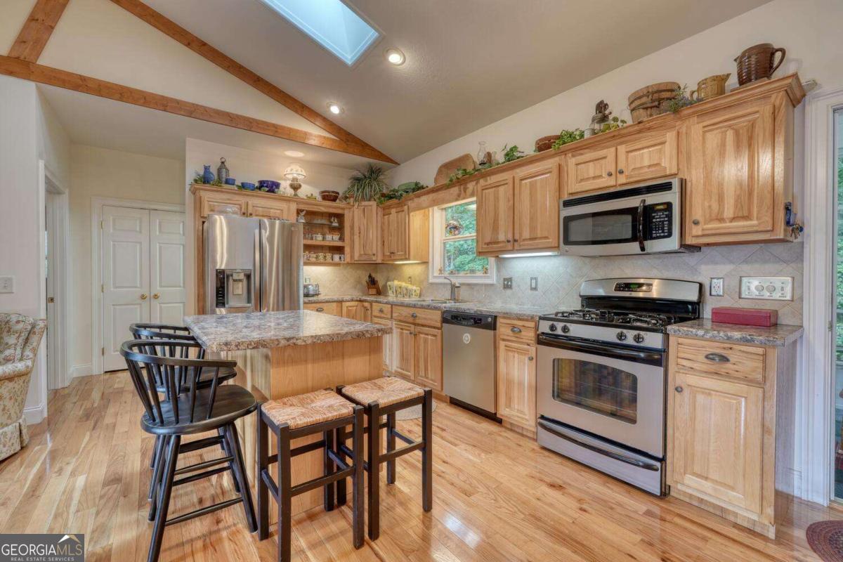 523 Sunnyside Shores Road Hiawassee, GA 30546 - Photo 11 of 55 a kitchen with granite countertop a stove top oven a sink dishwasher a dining table and chairs with wooden floor