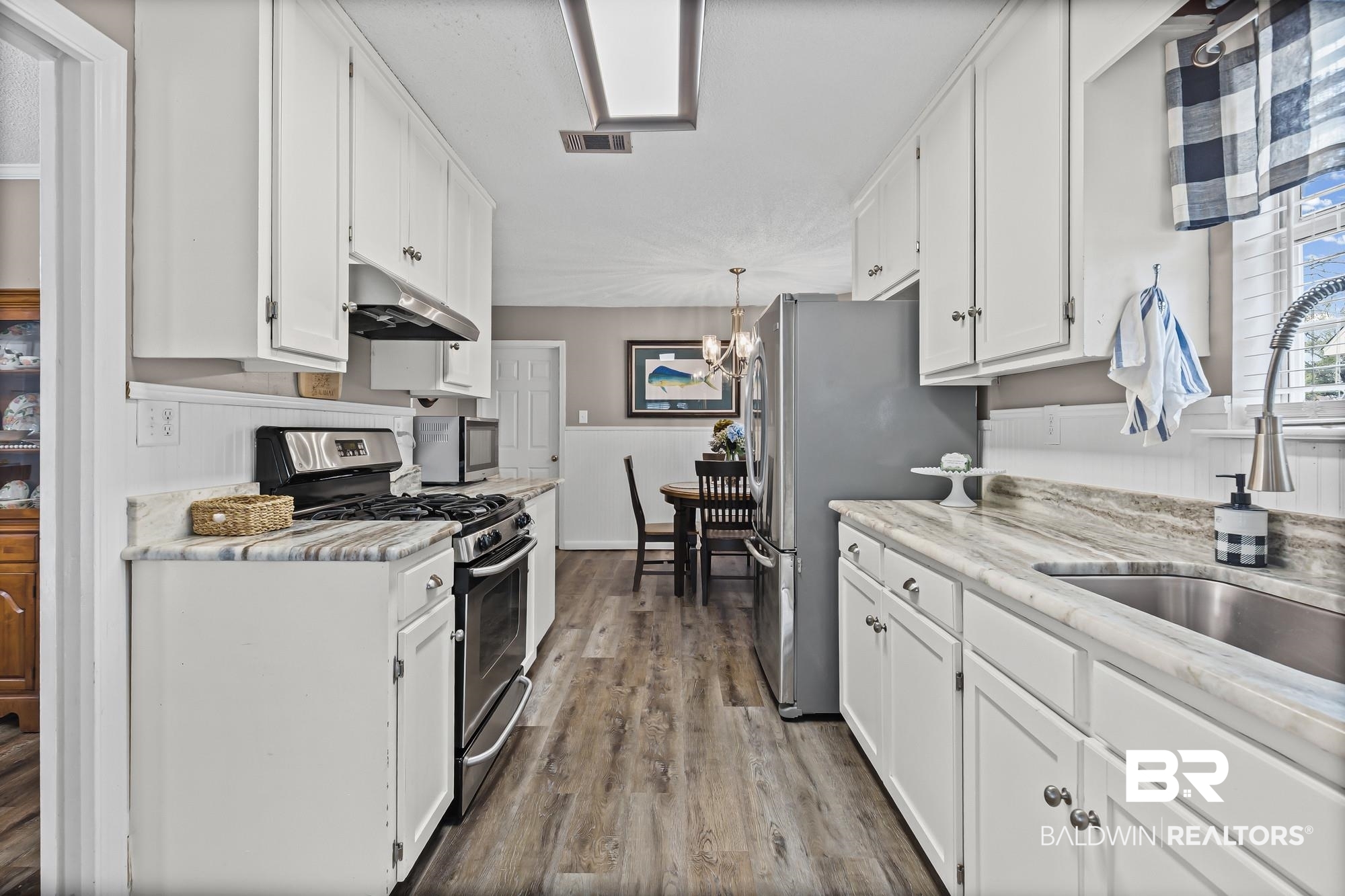 6609 Blakeley Court Mobile, AL 36695 - Photo 5 of 28 Kitchen with stainless steel appliances, white cabinetry, dark wood-style floors, suspended lighting, and light stone countertops