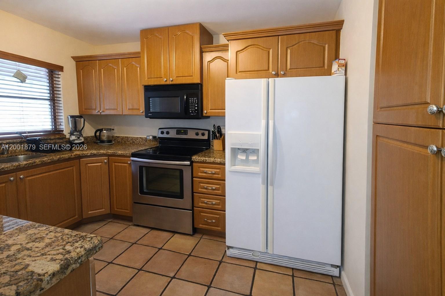5524 Constant Spring Terrace, Unit 213 Lauderhill, FL 33319 - Photo 7 of 16 a kitchen with granite countertop a refrigerator stove and microwave