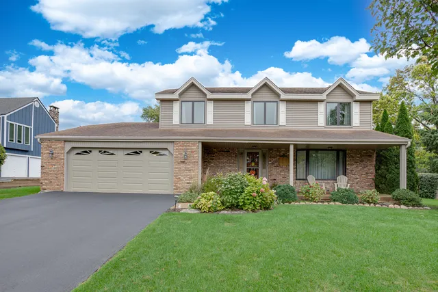 a view of a white house with a small yard and large trees