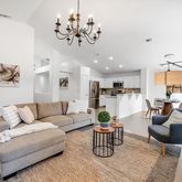 a living room with furniture kitchen view and a chandelier