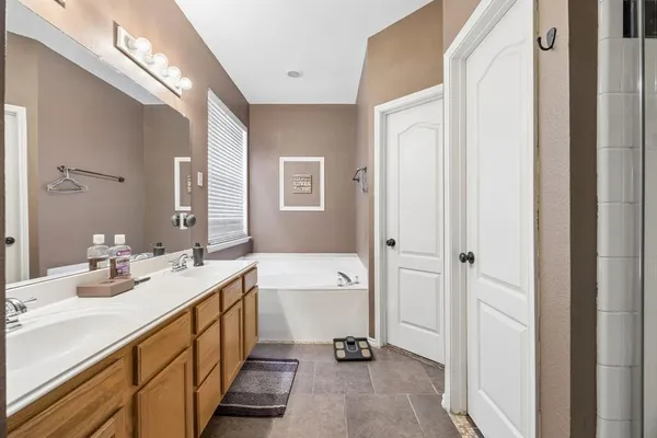 a bathroom with a double vanity sink a mirror and a bathtub