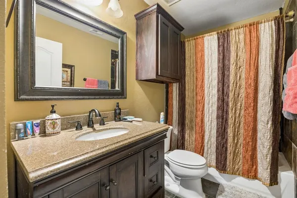 a bathroom with a granite countertop sink toilet and mirror