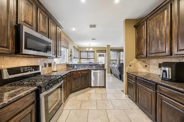 a kitchen with stainless steel appliances granite countertop a stove top oven a sink dishwasher a refrigerator and cabinets with wooden floor