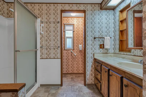 a bathroom with a granite countertop sink a mirror and a shower